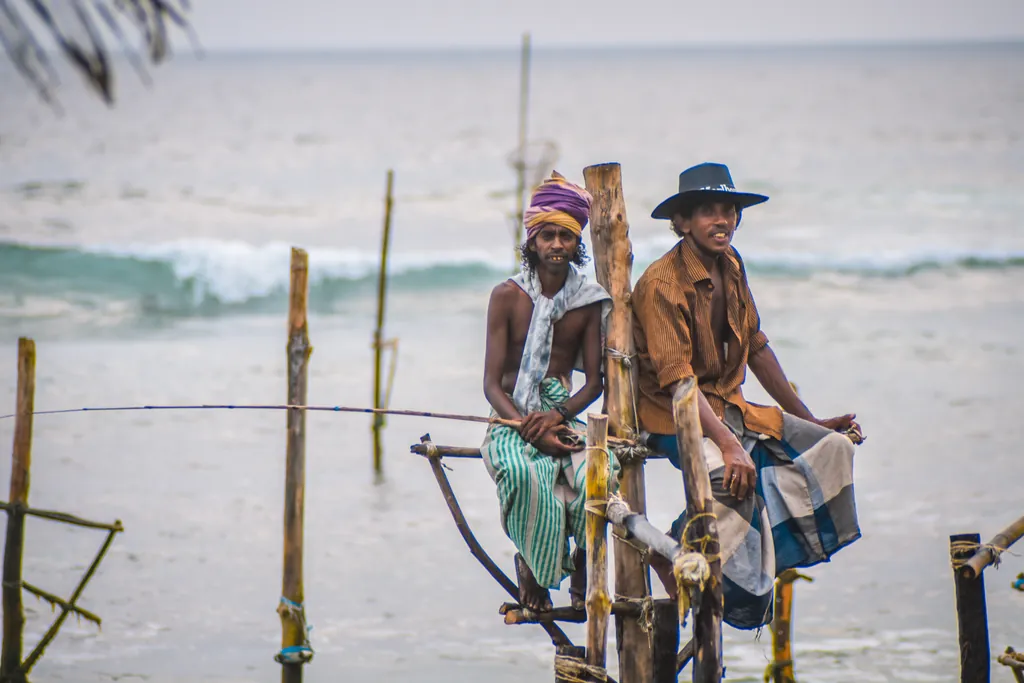 Fishermen perched on wooden stilts above the shallows at Ahangama