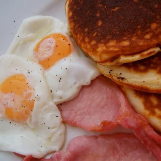 An American breakfast of pancakes, fried egg and bacon