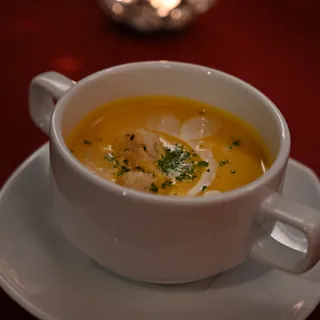A cup of creamy pumpkin soup finished with herbs