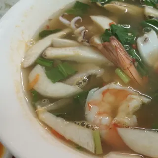 Thai tom yum soup with prawns and squid in a clear, aromatic broth