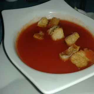 A bowl of creamy tomato soup topped with bread croutons