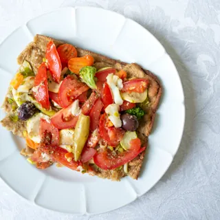 A vegetable pizza topped with peppers, tomato and olives
